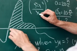 A man writing on a blackboard with a chalk.