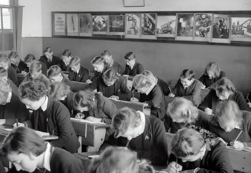 A black and white photo of a classroom with many students sitting at desks.