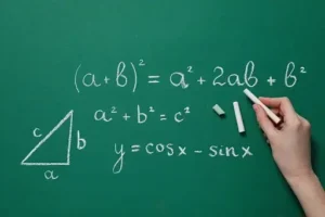 A person writing math formulas on a blackboard.